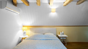 A bedroom with a bed, bedside table, lamp, and an air conditioning unit.