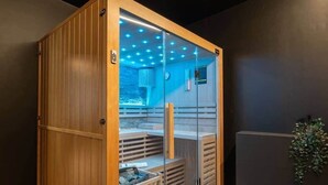 Eine Sauna mit Holzfassade, Glastüren und blauer Innenausleuchtung.