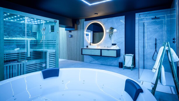 A modern bathroom with a large bathtub, a glass-enclosed shower area, and a vanity with a circular mirror.
