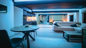 A modern living room with a round dining table, a sofa, and a kitchen in the background.
