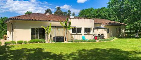 A two-story house with a tiled roof, large windows, and a well-maintained lawn.