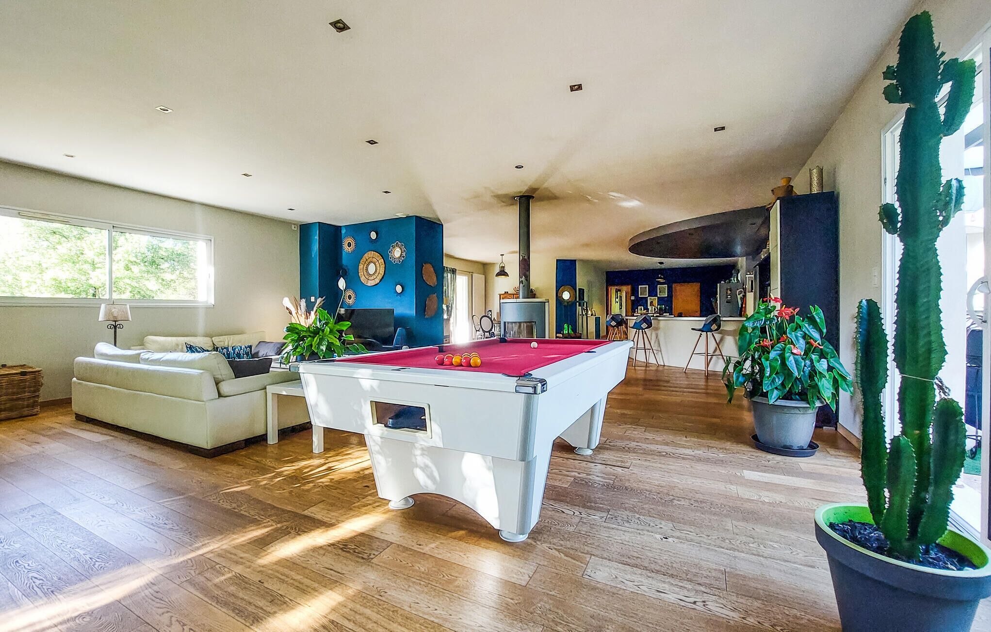 Ein geräumiges Wohnzimmer mit Billardtisch, einer Couch und einem Essbereich mit Stühlen.