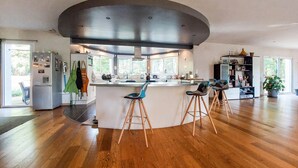 A modern kitchen with a central island, bar stools, and a large window. - 3 bedroom nice home in Sarliac (Sarliac)