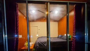 Ein Zimmer mit einem Bett, einem Nachttisch und einem Deckenventilator.