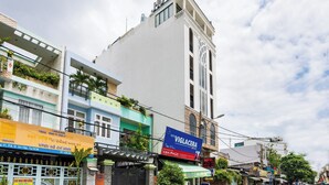 Ein Hotel mit einem großen 'HOTEL'-Schild oben, einem großen blauen Schild für 'VIGLACERA' in der Mitte und verschiedenen Geschäften entlang der Straße.