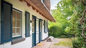 Een traditioneel gebouw met rieten dak, witte muren en donkere luiken.