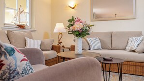 Een gezellige woonkamer met een bank, een klein rond tafeltje, een lamp en een decoratieve vaas.