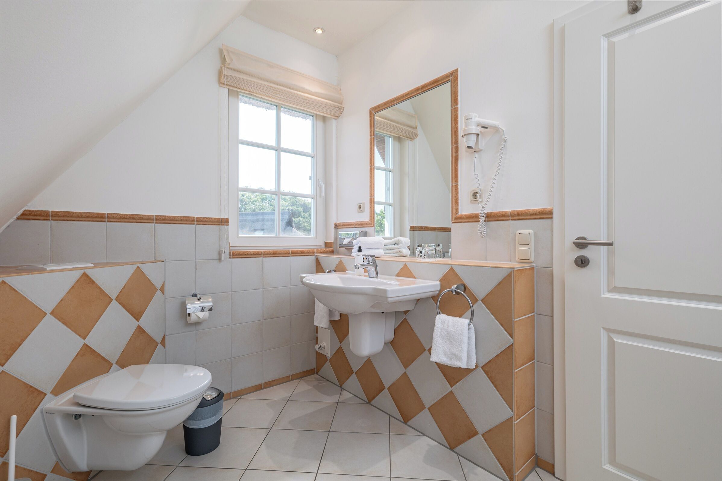 Een badkamer met toilet, wastafel en spiegel.