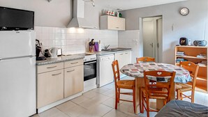 Cocina compacta con comedor, que incluye una mesa con sillas, un sofá y un televisor sobre la encimera de la cocina.