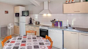 Una cocina compacta con una mesa de comedor, un refrigerador, una estufa y un lavabo.