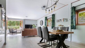 A modern living room with a dining area, a sofa, a TV, and a large window with curtains. - Amazing home in Erm with WiFi (Erm)