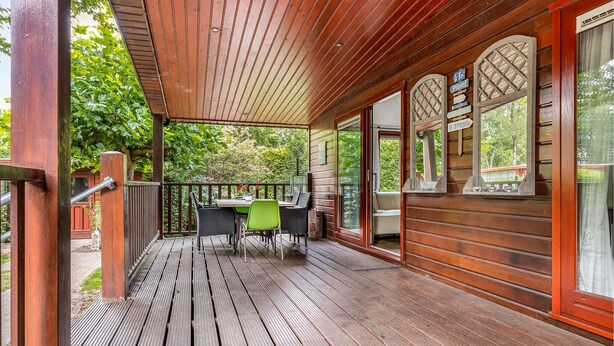 A wooden deck with a table and chairs, surrounded by glass doors and windows. - Amazing home in Erm with WiFi (Erm)