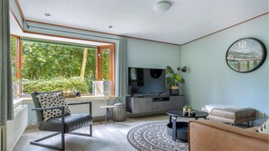 A modern living room with a sofa, a coffee table, a TV, and a dining area with a table and chairs.