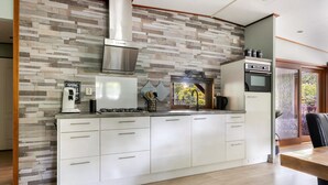A modern kitchen with a built-in stove, oven, and microwave. It features a wooden countertop, white cabinetry, and a herringbone-patterned backsplash.