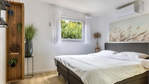 A bedroom with a bed, a window, a wooden wardrobe, and a wall-mounted air conditioner. - 1 bedroom stunning home in Erm (Erm)