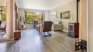 A spacious living room with a wooden floor, a sofa, a chair, a TV, and a fireplace. - 2 bedroom pet friendly home in Erm (Erm)