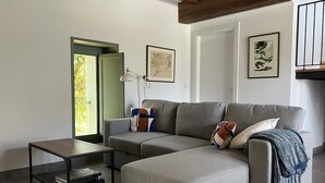 Ein modernes Wohnzimmer mit einem Ecksofa, einem kleinen Beistelltisch und einem Bücherregal.