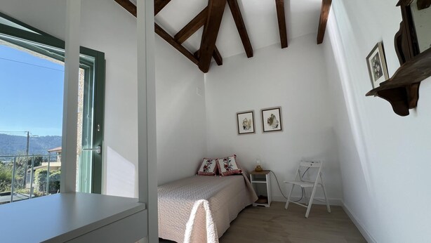 Un dormitorio con una cama, un escritorio y una silla. Hay dos cuadros en la pared.