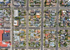 An aerial view of a residential area with streets, houses, and parked cars.