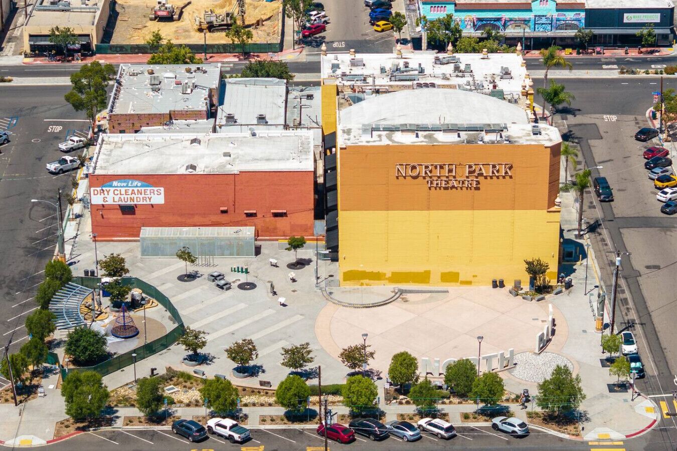 Un edificio a più piani con un grande cartello che riporta 'North Park Theatre' e un cartello per 'New Life Dry Cleaners & Laundry'.