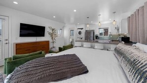 Une chambre d’hôtel moderne dotée d’un grand lit, d’une télévision, d’un coin repas et d’une cuisine.