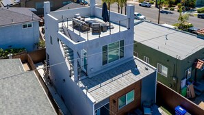 Un immeuble moderne à plusieurs étages, doté d’une terrasse sur le toit, de grandes fenêtres et d’un escalier apparent.