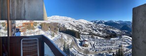 A snow-covered mountainous landscape with a parking area and buildings in the foreground. - Family studio with balcony at the foot of the ski area (Villarembert)