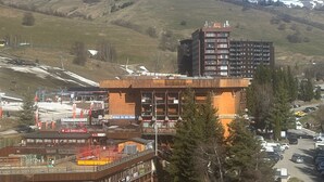 Een hotel met een skipiste op de achtergrond, een parkeerplaats en uitzicht op een berg.