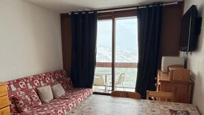 Een knus ingerichte kamer met een gestreept bankje, een houten tafel en stoelen.