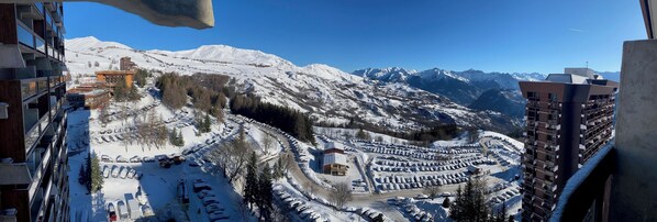 A snow-covered mountain village with a parking lot and buildings. - Family studio with balcony at the foot of the ski area (Villarembert)