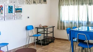 Un comedor con una mesa y sillas azules, un carrito pequeño negro y un piso con baldosas.
