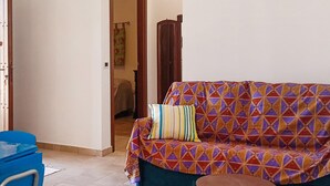 Una sala de estar con un sofá estampado, una mesita redonda y una silla azul.