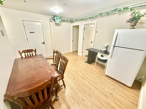 A dining area with a wooden table and chairs, a white refrigerator, and a small kitchen counter. - Private Guest Suite, Two Parking Spaces (Maple Ridge)
