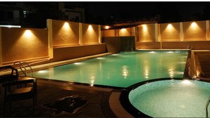 Una piscina con un jacuzzi integrado, rodeada de muros con iluminación empotrada.