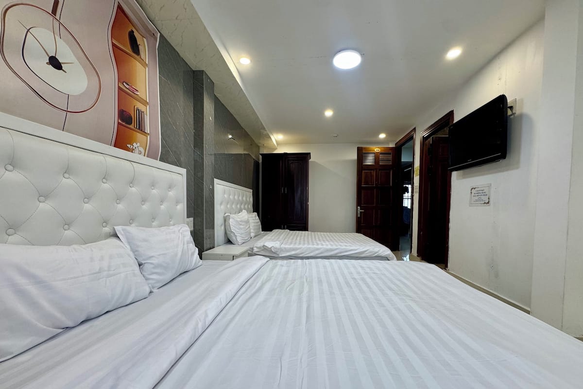 Een hotelkamer met twee bedden, een grote klok aan de muur en een televisie.