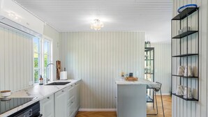 A modern kitchen with a central island, built-in oven, and a dining area with a view.