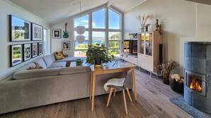 Una sala de estar moderna con un ventanal grande, chimenea y comedor.