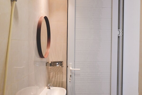 A bathroom with a sink, a towel rack, and a glass shower enclosure.