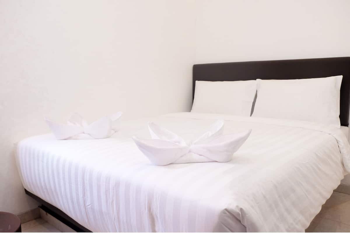 A neatly made bed with white linens and two decorative pillows.