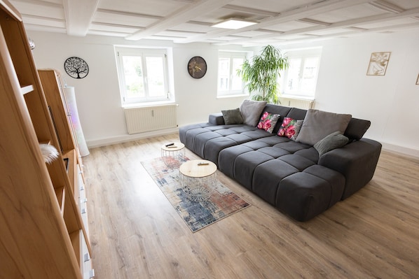 A modern living room with a dark grey sectional sofa, a round coffee table, and a large potted plant.