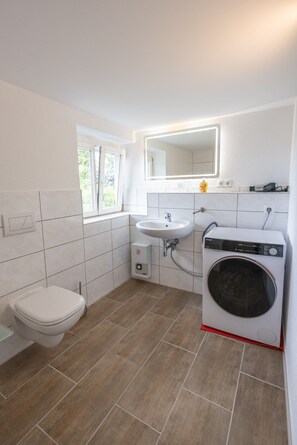 A compact bathroom with a toilet, sink, and washing machine.