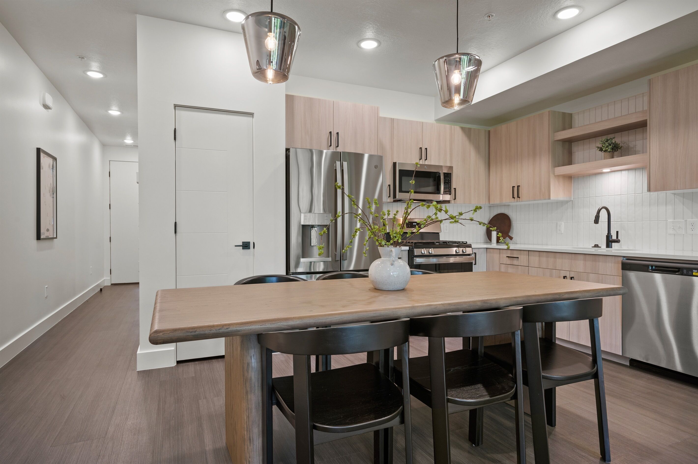 A modern kitchen with stainless steel appliances, wooden cabinets, and a central island with bar stools.