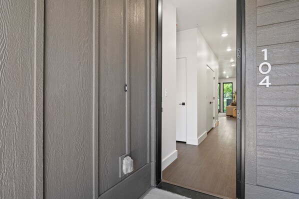 A modern hallway with a wooden door and a number '104' on the wall.