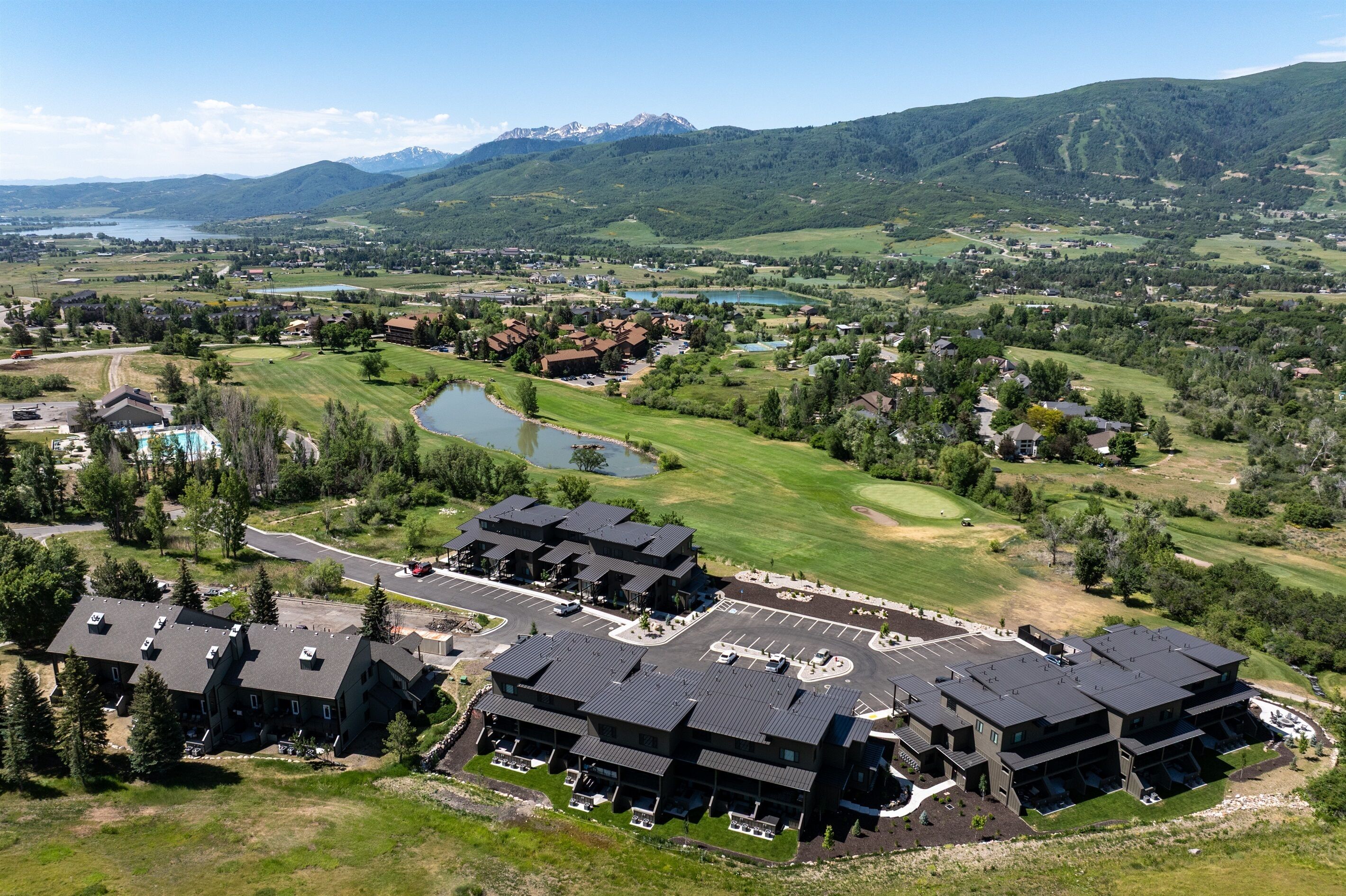 A large hotel complex with multiple buildings, a parking lot, and a golf course in the background.