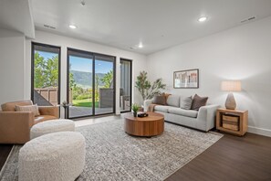 A modern living room with a sofa, ottomans, a coffee table, and a lamp.