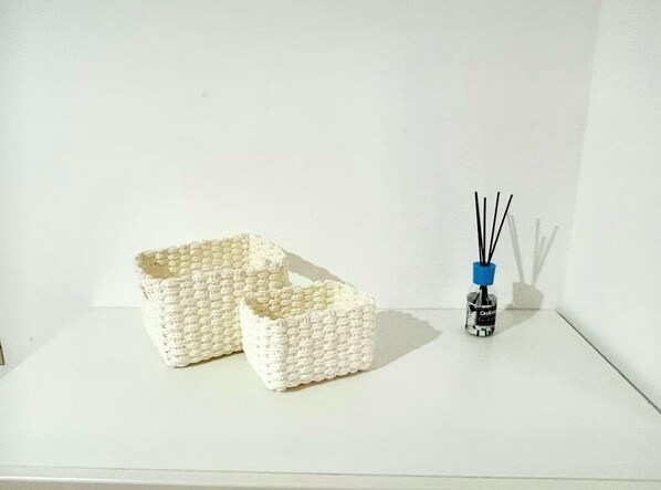 Two white woven baskets on a white surface with a small black and blue object beside them.