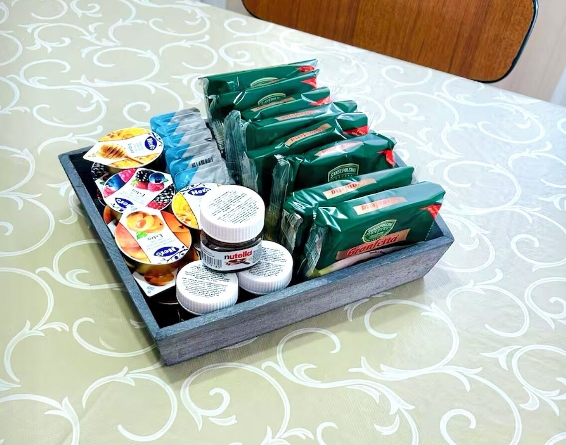 A tray with various food items and packaged goods on a table with a patterned tablecloth.