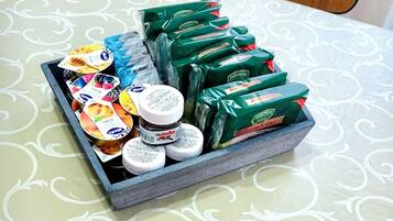 A tray with various food items and packaged goods on a table with a patterned tablecloth.