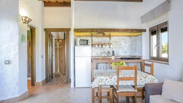 Cocina compacta con microondas, refrigerador y comedor con mesa y sillas.