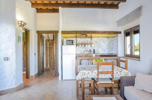Cocina compacta con microondas, refrigerador y comedor con mesa y sillas.